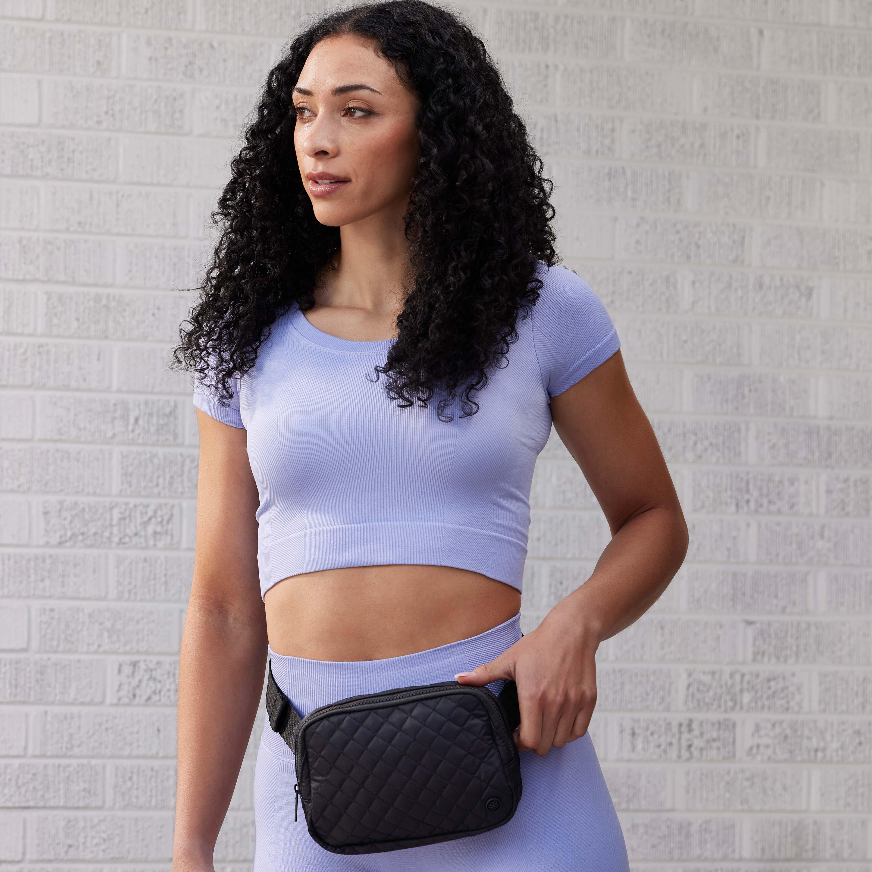 Person standing outside wearing the Sidekick Waist Pack - Quilted XL around the waist 